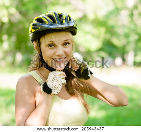 woman putting biking helmet on outside during bicycle ride.