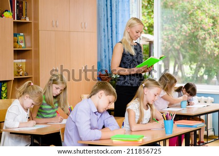 students in the class write assignments that reads them a young teacher