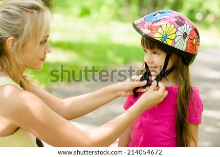 closeup young mother dresses her daughter\'s bicycle helmet