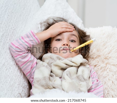 sick girl lying in bed with a thermometer in mouth and touch his forehead