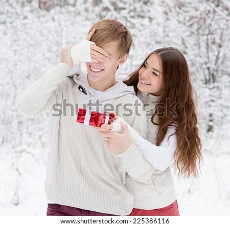 girl covering boyfriends eyes with hands and giving a gift