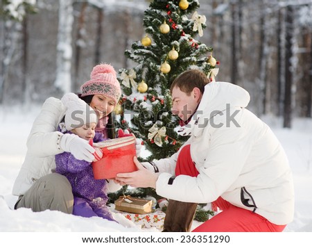 father gives his daughter a gift for Christmas in winter forest