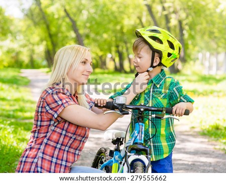 mother taking care of her son, wearing his bicycle helmet