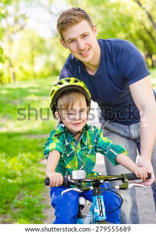young father teaches his son to ride a bike