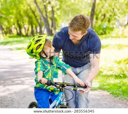 Young father teaches his son to ride a bike
