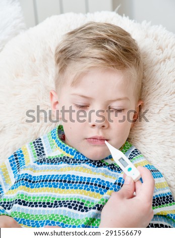 Sick kid with high fever laying in bed and mother checks the temperature