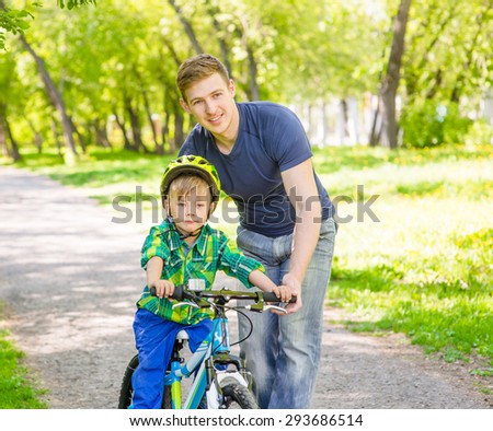 happy father teaches his son to ride a bike
