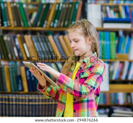 Teen girl using a tablet computer in a library