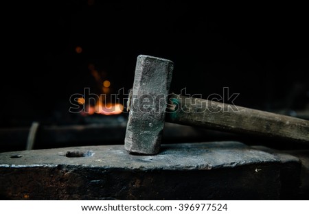 blacksmith hammer on the anvil against the background of fire