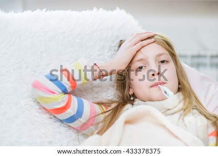 Sick girl with thermometer in mouth touching her forehead