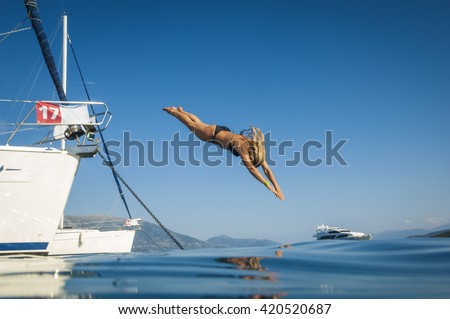 Jung woman jumping from sailing boat to sea