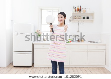 Young Asian woman with cooking utensils in the kitchen