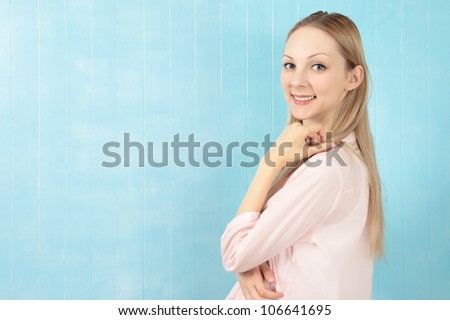 Half body portrait of happy young woman with long blond hair, blue background with copy space.