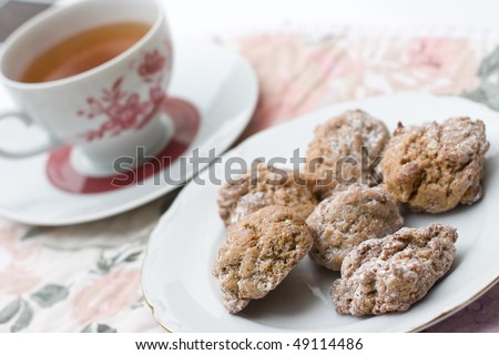 plate with fresh cookies and cup of black tea on floral table mat