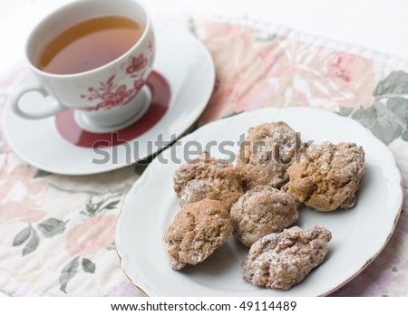 plate with fresh cookies and cup of black tea on floral table mat