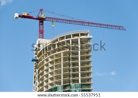 Construction site - modern semicircle shaped building and the red crane.
