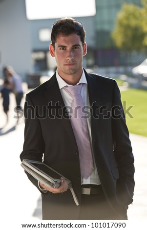 Elegant young businessman using his PC tablet while walking