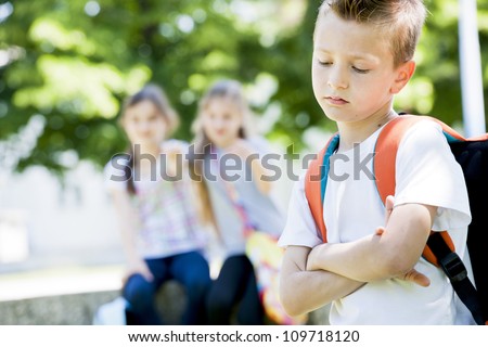 Two little girls potning at the little sad boy focus on foreground Two little girls potning at the little sad boy focus on foreground