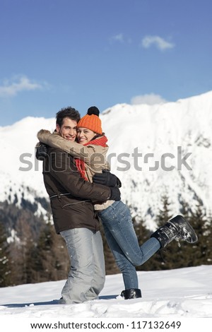 Young couple on the snow with Christmas gift