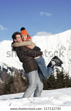 Young couple on the snow with Christmas gift