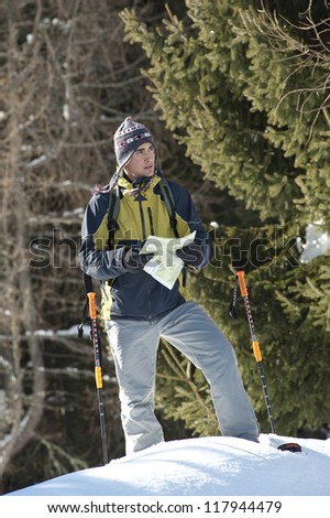 Young man looking at map, while walking with snow shoes