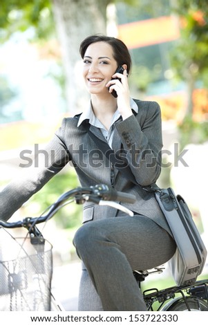 Businesswoman biking  and speaking on the phone