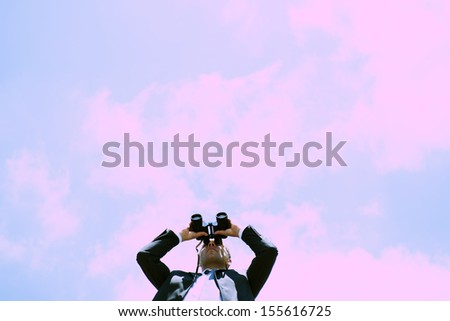 Businessman looking through binoculars, low angle view