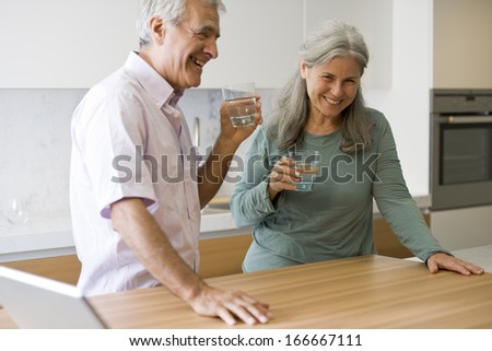 Senior couple drinking water in the kitchen