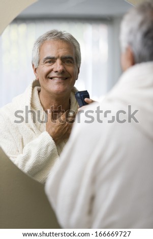 Senior happy man shaving his in front of the mirror