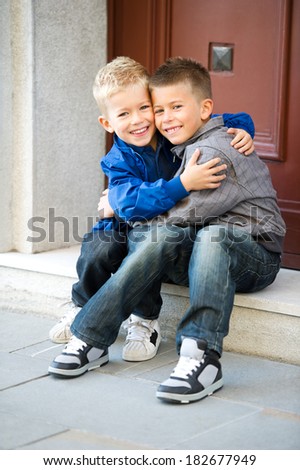 Happy brother sitting on door steps and embracing