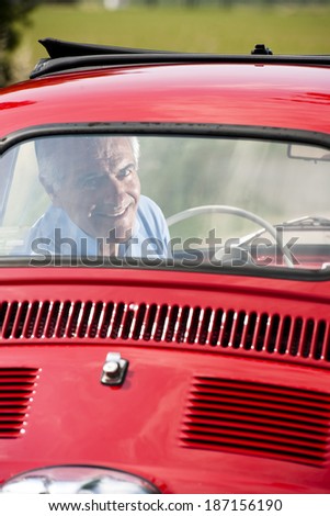 Happy senior man in a vintage car