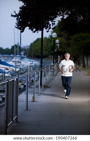 Active senior man running on a dock in the evening light