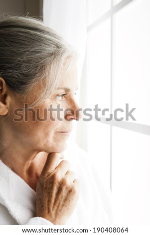 Portrait of a pensive senior woman looking outside the window