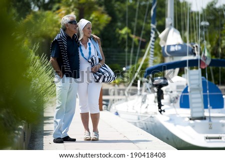 Happy senior couple walking on a dock in summer