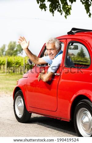 Senior man driving a vintage car and waving