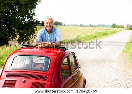 Happy senior man in a vintage car
