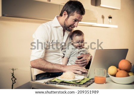 Multi-tasking father with baby while working at home