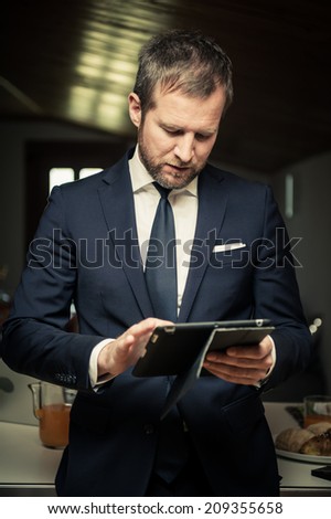 Young businessmen using PC tablet at home before breakfast