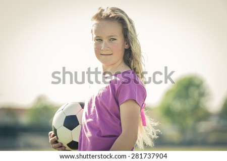 Young female soccer player posing with ball