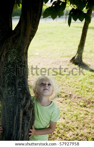 Little girl hugging a tree and looking up. Concept: future generations