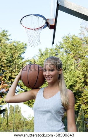 Young woman holding basketball at basketball court