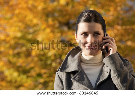 Young woman on the phone, Autumn background