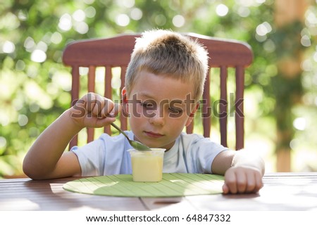 Cute little boy eating pudding outside