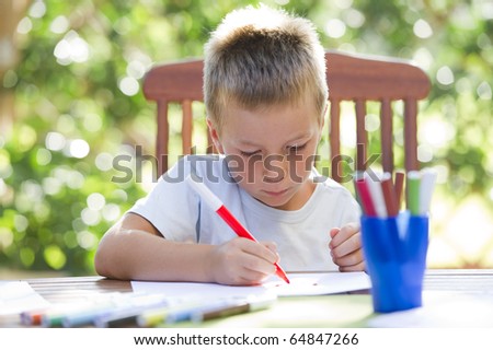 Cute little boy coloring outside