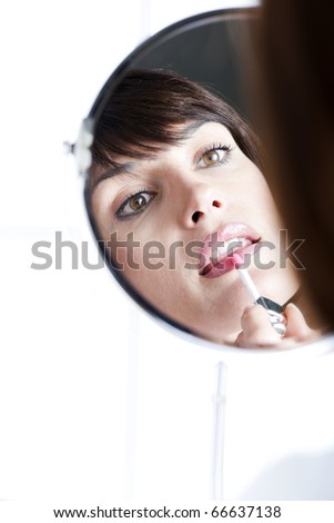Woman applying lipstick in the mirror