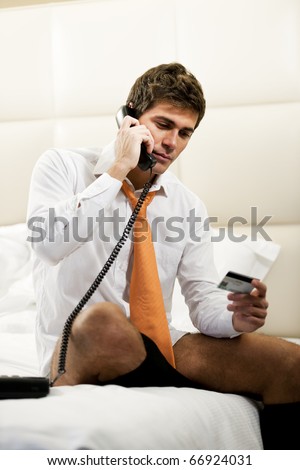 Relaxed Businessman Making Phone Reservation in hotel room