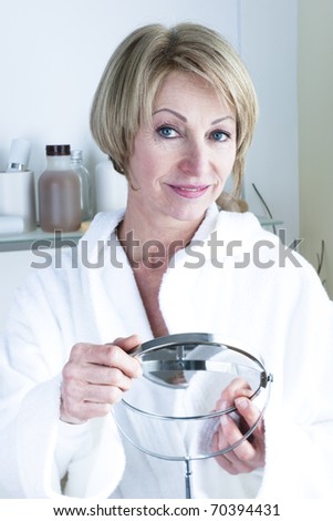 Beautiful mature woman holding mirror