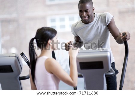 Two young people speaking while exercising at gym