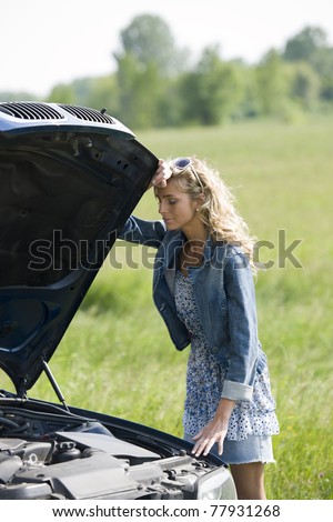 Worried young woman with her broken car, calling for assistance