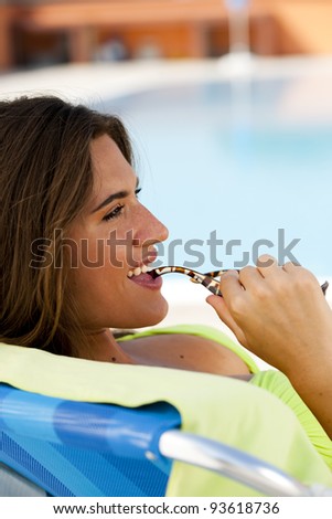 Beautiful young woman lying on deckchair by swimming-pool